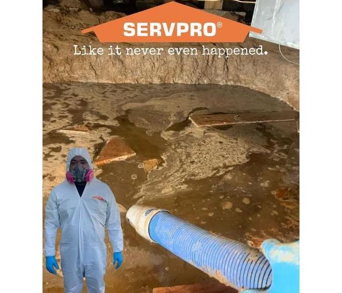 Water under a crawl space with tech dressed in PPE 