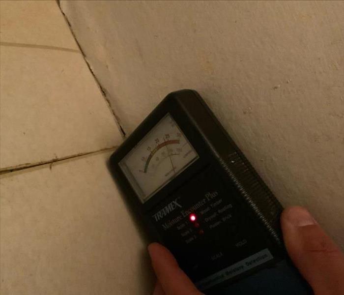 Water meter against a wall being used to detect moisture 